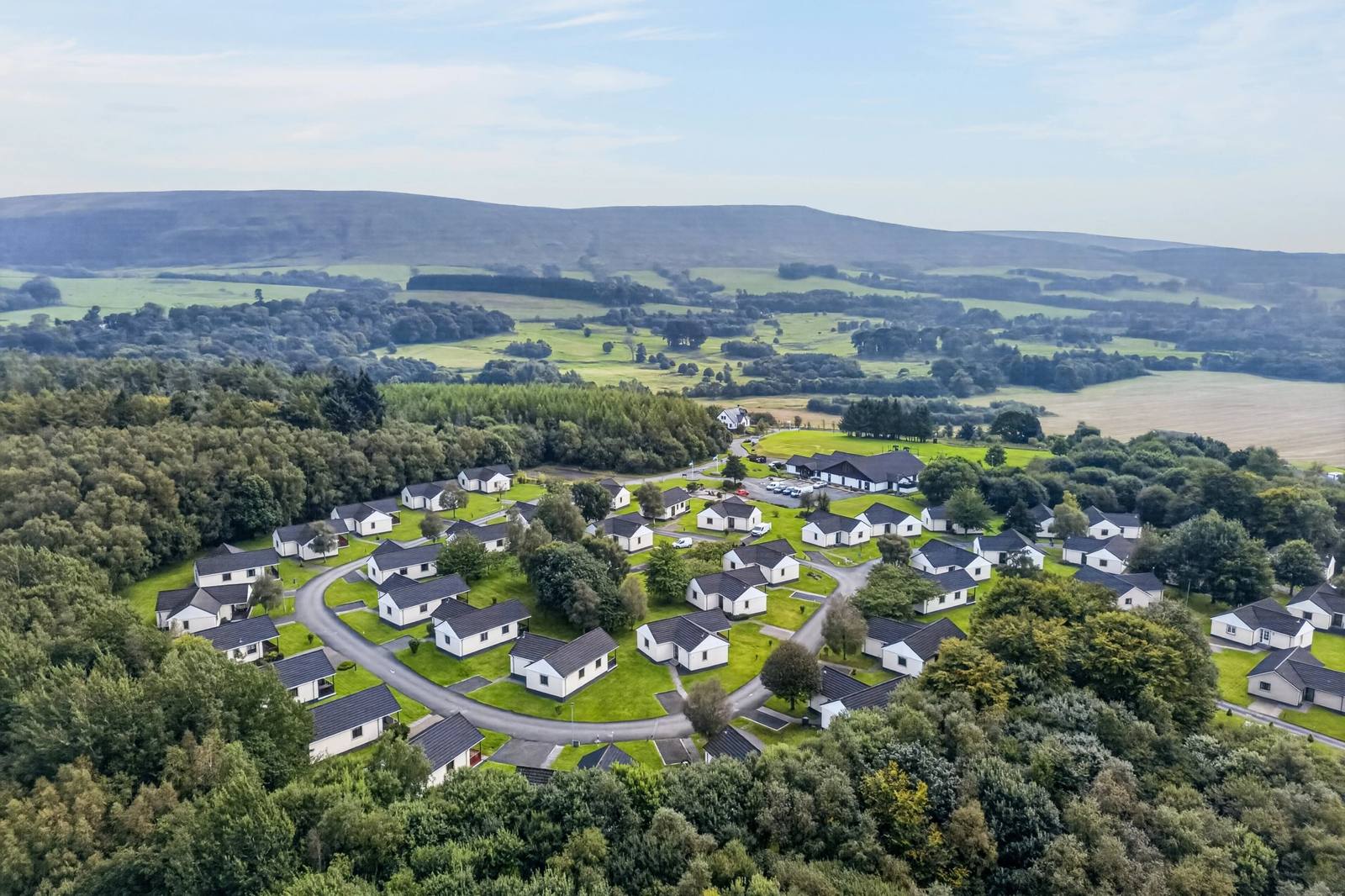 Aerial view of the lodges at Brunston Country Retreat among woodland in South Ayrshire
